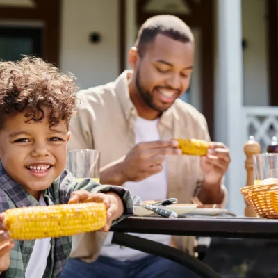 wgs-blogs-smiling-boy-and-man-eating-corn-on-cob-2026-01-05-23-53-54-utc-400x400-v01 smiling father and son eating corn on cob
