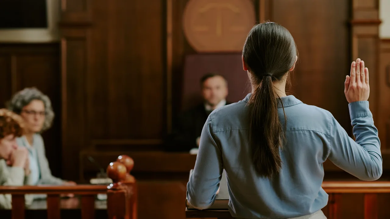 Domestic Violence: Signs, Facts, and Best Resources woman raising her hand in court